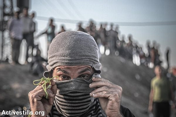 A Palestinian adjusts his mask during a protest near the Gaza border Strip, near Nahal Oz crossing, October 30, 2015. Since the beginning of October, more than 60 Palestinians have been killed in shootings and clashes with Israeli forces in the occupied Palestinian territories and Israel, while eight Israelis have been killed in knife and gun attacks. (photo: Ezz Zanoun/Activesills.org)