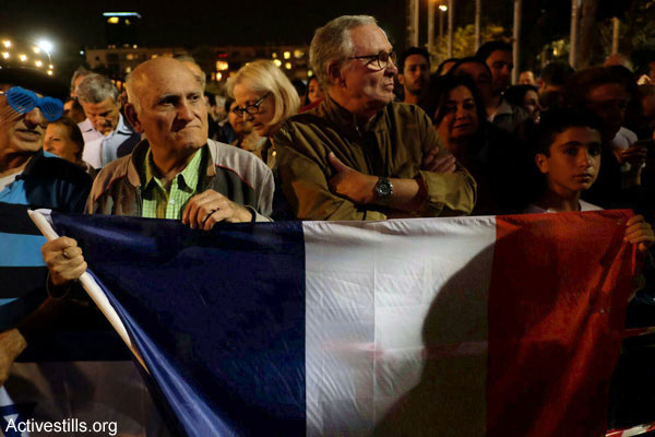Israeli men stand with a French flag at the Tel Aviv memorial for victims of the Paris terror attacks, November 14, 2015. (Yotam Ronen/Activestills.org)