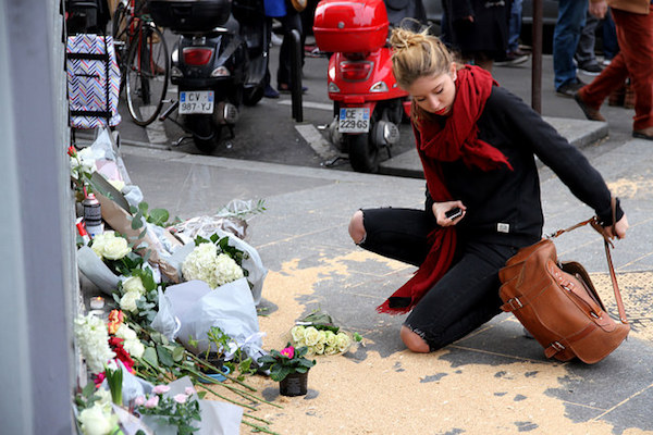 A woman lays flowers at an impromptu memorial a day after the Paris terror attacks, Le Petit Cambodge / Carillon, November 14, 2015. (Maya-Anaïs Yataghène/CC)