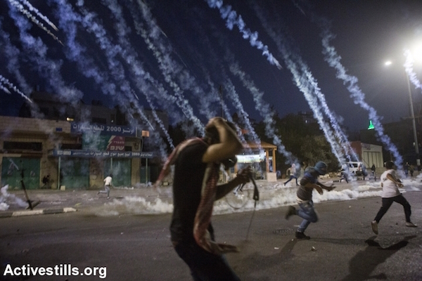 Palestinian youths run from tear gas during clashes with the Israeli army in the West Bank city of Bethlehem, November 13, 2015.  (Anne Paq/Activestills)