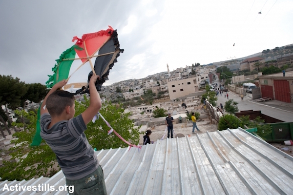 A boy launches a Palestinian flag kite during an event commemorating Nakba Day, Aida Refugee Camp, Bethlehem, West Bank, May 14, 2012. (Ryan Rodrick Beiler/Activestills.org)