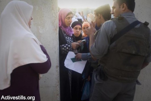 Israeli soldiers check Muslim Palestinian women's IDs as thousands try to pass through the Qalandiya checkpoint on the last Friday during Ramadan, September 3, 2010. Harsh restrictions by the Israeli army meant that many who attempted to pass were turned away, while others waited for a long time at the checkpoint in Ramallah. (Photo: Oren Ziv/Activestills)