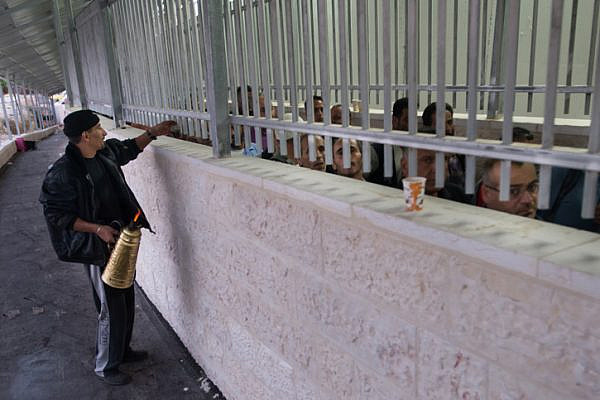 A street vendor sells coffee to Palestinian laborers waiting to cross from Bethlehem through an Israeli checkpoint into Jerusalem. (Photo by Activestills.org)
