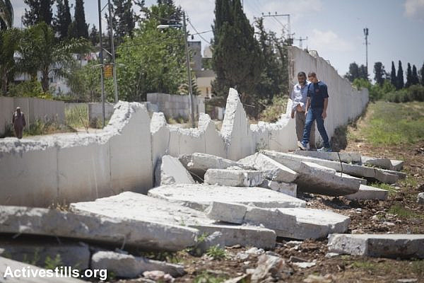 A damaged section of the wall separating Lod’s Palestinian neighborhood of Pardes Shanir and the Jewish town of Nir Tzvi, 2013. (Oren Ziv/Activestills.org)