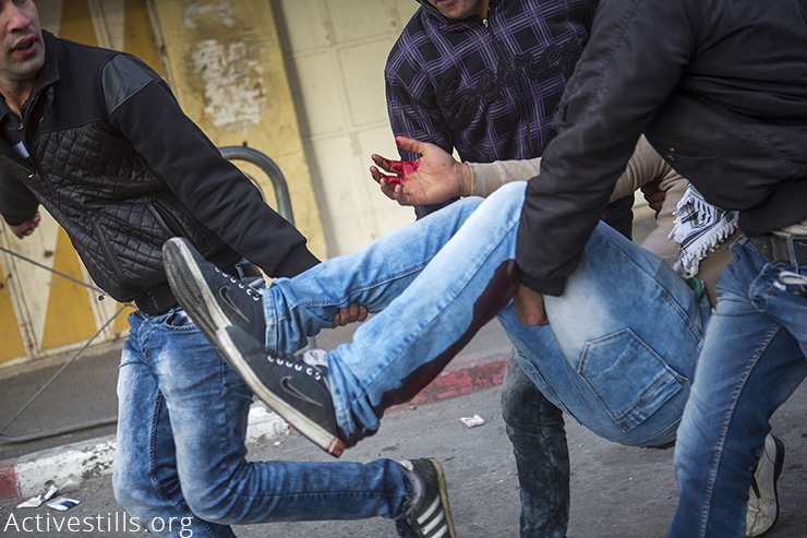 Palestinians carry an injured youth after he was shot by an Israeli sniper during clashes with the Israeli army  in the West Bank city of Hebron, November 4, 2015.  Since October 1st, 73 Palestinians have been killed by Israeli forces, and 11 Israelis in attacks by Palestinians. More than 6,000 Palestinians and over 80 Israelis were injured, and 1,195 Palestinians including 177 underage children were arrested. (Activestills.org)