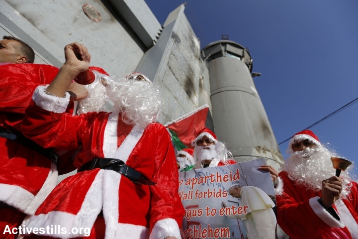 Palestinians dressed up as Santa Claus demonstrate at the separation wall, Bethlehem, December 18, 2015. (photo: Anne Paq/Activestills.org)