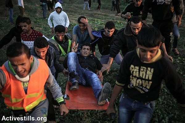 Palestinians carry an injured protester during clashes with Israeli forces near the Israel-Gaza border, near Nahal Oz crossing, Nobember 20, 2015. (Ezz Zanoun/Activestills.org)