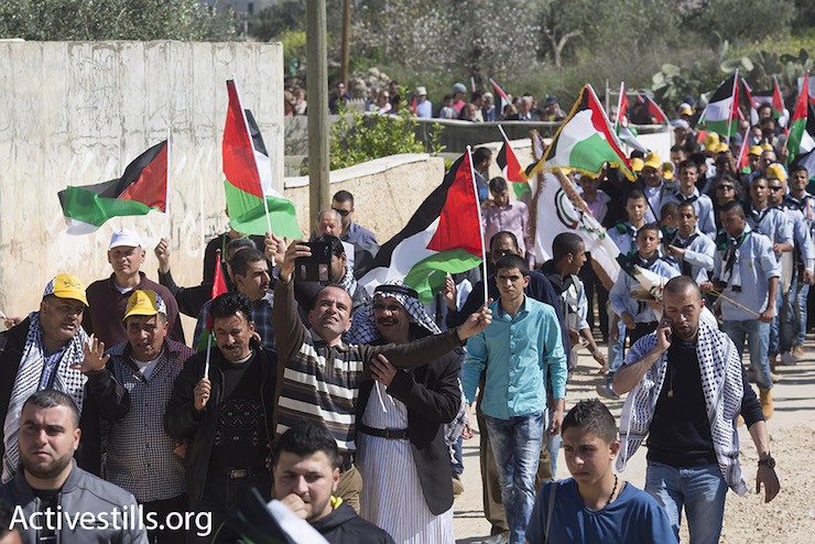 Palestinians, Israelis and internationals march through the West Bank village of Bil’in, protesting Israel’s expropriation of village land with the separation barrier, February 19, 2016. (Oren Ziv/Activestills.org)