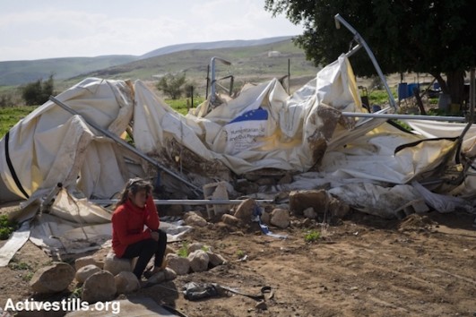 A child sits next to her demolished shack, that was provided by the EU is seen the village of Fasayil in the Jordan valley, West Bank on February 10, 2016. (Oren Ziv/Activestills.org)