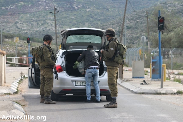 Israeli soldiers inspect a vehicle at the Enav checkpoint separating the West Bank Palestinian cities of Nablus and Tulkarem, January 11, 2016. (Ahmad Al-Bazz/Activestills.org)