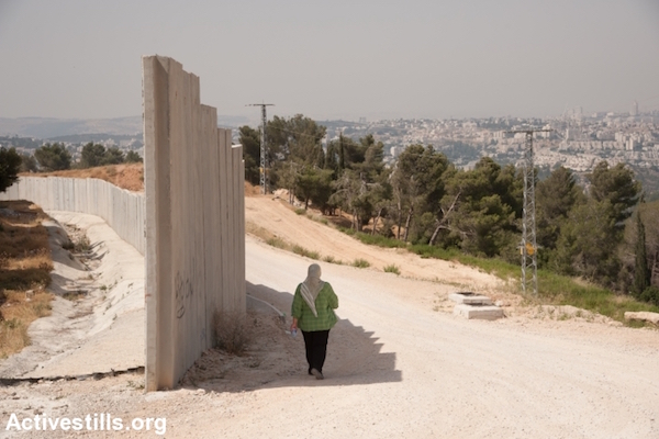 A Palestinian woman walks along an unfinished section of the separation barrier in the West Bank town of al-Walaja. (Ryan Rodrick Beiler/Activestills.org)