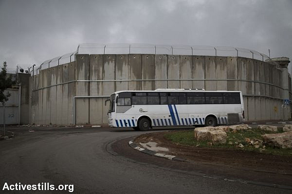 A Palestinian bus drives along Israel’s separation wall between Jerusalem and the West Bank city of Jerusalem, February 23, 2016. (Oren Ziv/Activestills.org)