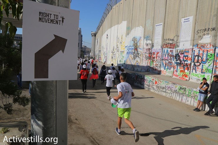 Participants in the 2016 Palestine Marathon run along Israel’s concrete separation wall, Bethlehem, West Bank, April 1, 2016. (Ahmad al-Bazz/Activestills.org)