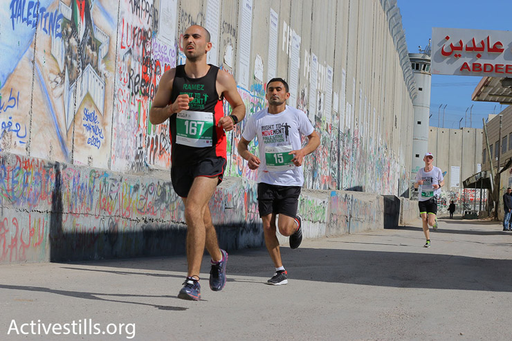 Participants in the 2016 Palestine Marathon run along Israel’s concrete separation wall, Bethlehem, West Bank, April 1, 2016. (Ahmad al-Bazz/Activestills.org)