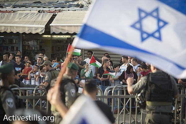 Behind police barricades, Palestinian residents of Jerusalem hold a counter-protest against the nationalist display in their neighborhood, June 5, 2016. In years past physical and verbal violence against Palestinians was a central feature of the  march. (Oren Ziv/Activestills.org)