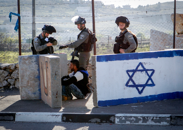 Israeli border policemen detain a Palestinian man at a checkpoint in Beit Enoon, near the West Bank city of Hebron, April 04, 2016. (Wisam Hashlamoun/FLASH90)