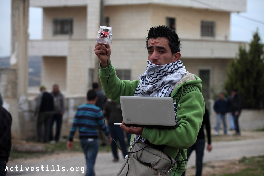 A Palestinian activist streams live video during the weekly demonstration in Kafr Qaddum, West Bank, December 30, 2011. 