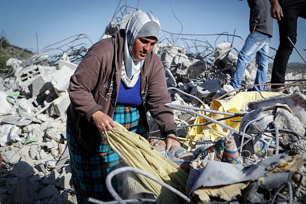 A Palestinian woman sorts through the rubble of her demolished home in the West Bank village of Surif, April 4, 2016. The Israeli army demolished the home because it says it was unauthorized. (Wisam Hashlamoun/FLASH90)