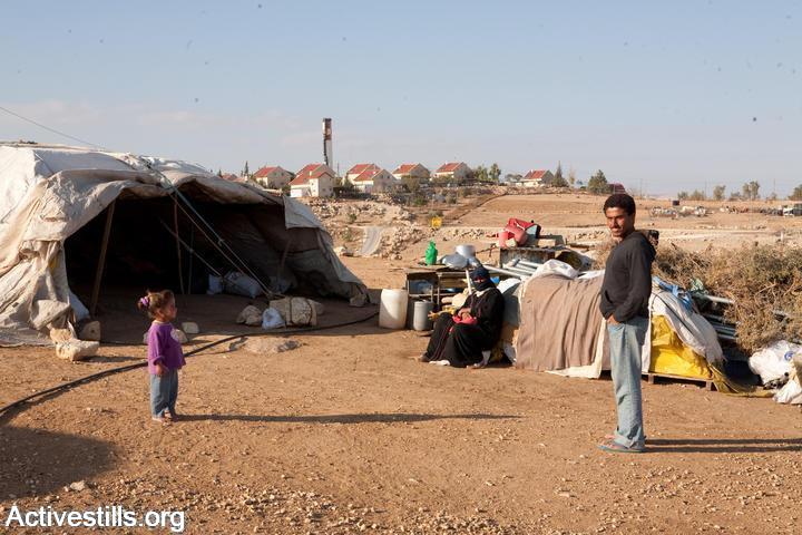 A Palestinian home in the village of Umm al-Kheir is seen against the backdrop of the Israeli settlement of Carmel, South Hebron Hills, West Bank. (Keren Manor/Activestills.org)
