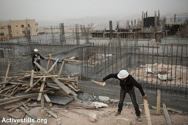 Palestinian construction workers work at a site in Jerusalem's Ramat Shlomo neighborhood. (Tali Mayer/Activestills.org)