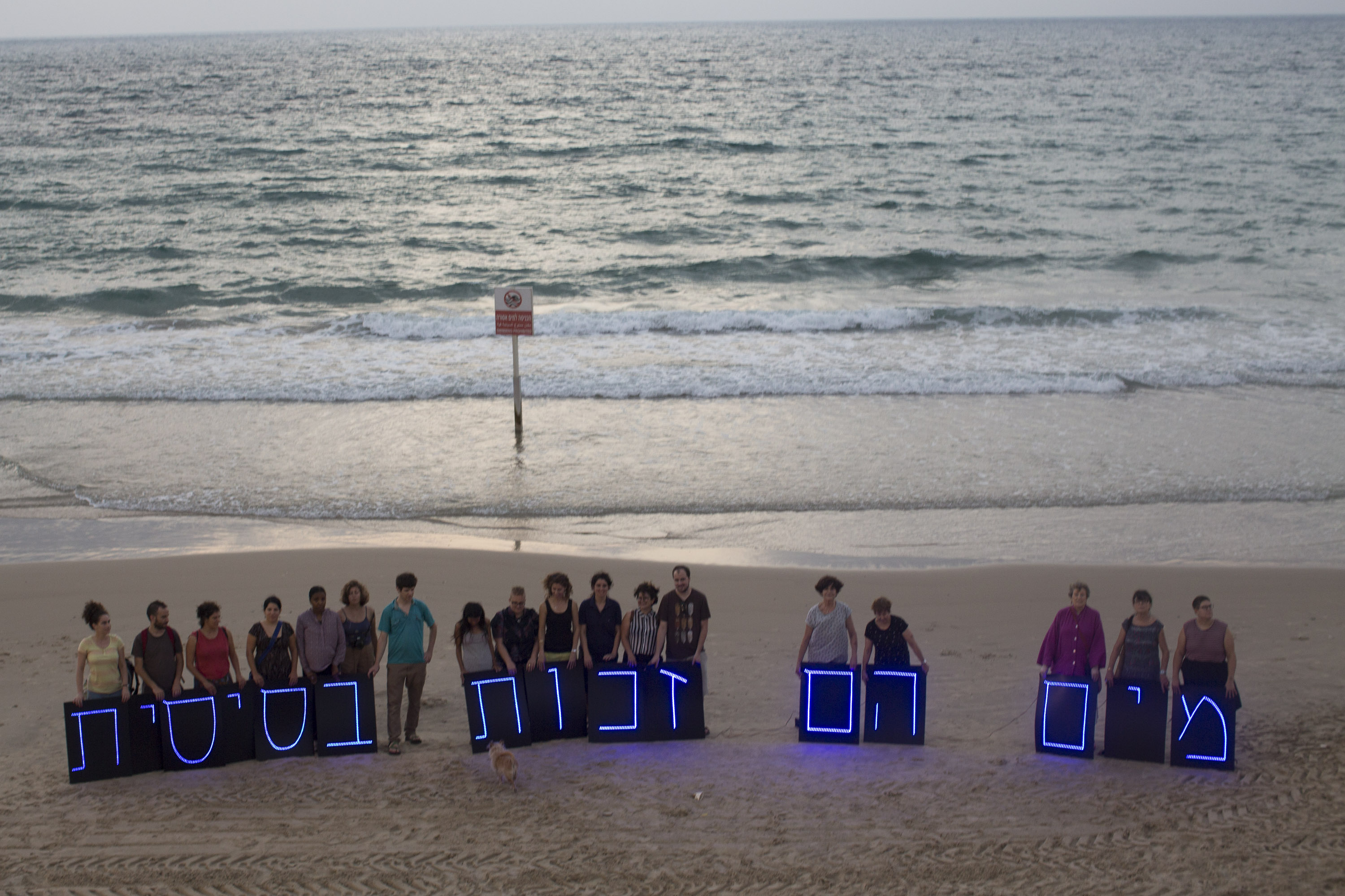 Israeli activists hold illuminated letters that spell out "Water is a basic right" as part of an international light installation coordinated by the "Water Coalition," calling for equal water rights for Palestinians, August 14, 2016. (Oren Ziv/Activestills.org)