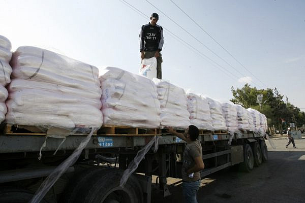 File photo of Palestinian workers offloading a truck full of aid in the Gaza Strip. (Abed Rahim Khatib/Flash90)