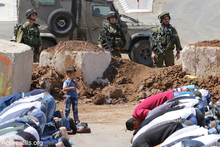 Palestinians from the village of Beita hold Friday prayers at an Israeli military roadblock in protest of the collective punishment, September 23, 2016. (Ahmad Al-Bazz / Activestills.org)