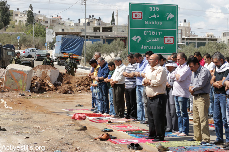 Palestinians from the village of Beita hold Friday prayers at an Israeli military roadblock in protest of the collective punishment, September 23, 2016. (Ahmad Al-Bazz / Activestills.org)