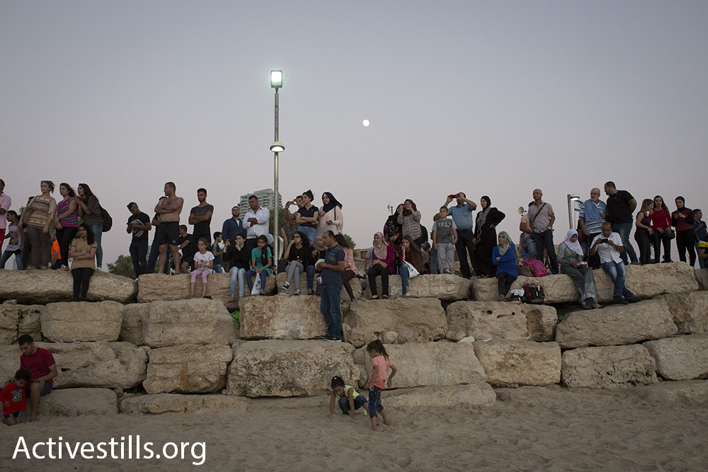 Palestinian families watch the sunset at the beach north of Jaffa during Eid al-Adha, September 14, 2016. (Oren Ziv/Activestills.org)