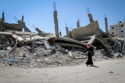 A Palestinian woman walks past the rubble of a home that was destroyed by Israel during the 2014 war, Rafah, Gaza Strip, July 30, 2015. (Abed Rahim Khatib / Flash 90)