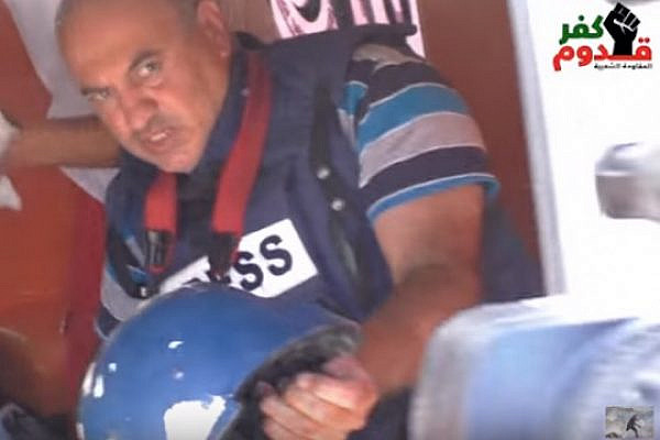 Nidal Eshtayeh holds his damaged helmet while receiving treatment in an ambulance after being shot by Israeli troops in Kafr Qaddum, September 2, 2016. (Screenshot)