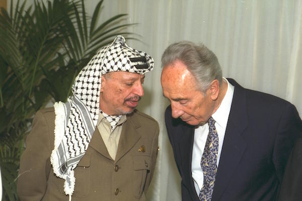 PLO Chairman Yasser Arafat speaks with then Foreign Minister Shimon Peres in Paris, July 6, 1994. (Sa’ar Yaacov/GPO)