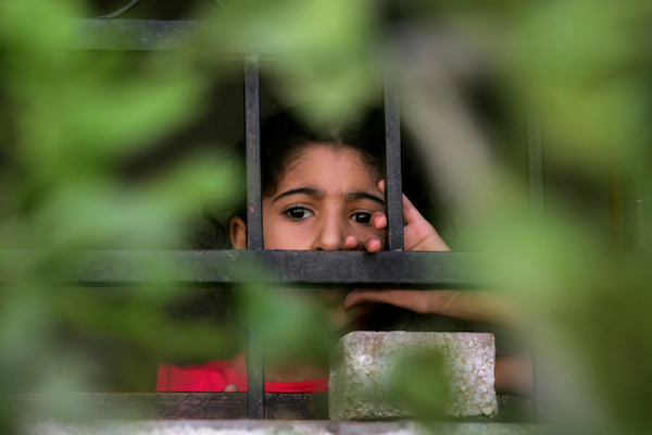 A young Palestinian boy looks through a window at a funeral for family members who were killed by an Israeli air strike in Gaza, August 27, 2014. (Abed Rahim Khatib/Flash90)