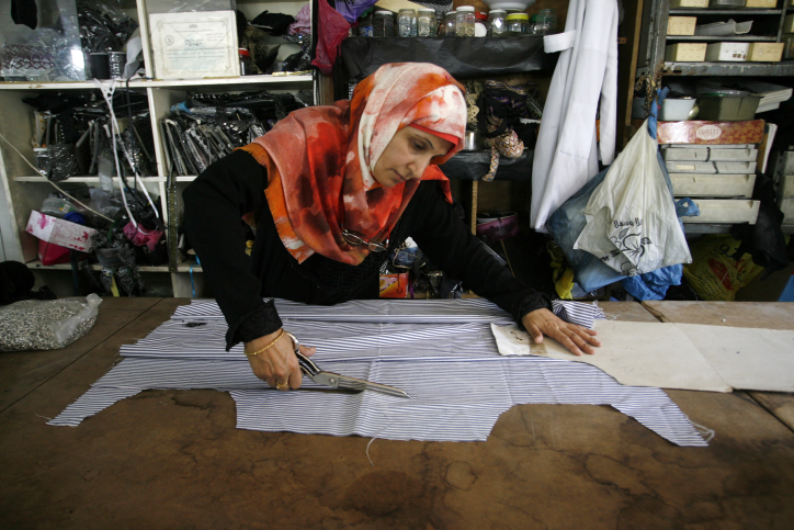 A Palestinian woman tailor sews clothes at a workshop in Rafah in the southern Gaza Strip, September 4, 2014. (Abed Rahim Khatib/Flash90)