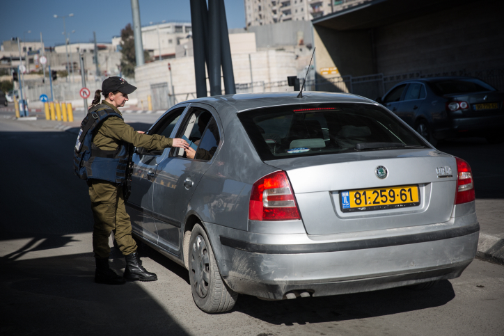 An Israeli soldier at a checkpoint examines the ID cards of ’48 Palestinians traveling in a car with yellow, Israeli license plates. (Illustrative photo by Hadas Parush/Flash90)