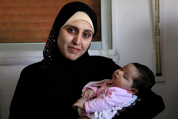 A Syrian refugee woman with her 25-day-old daughter, at an International Rescue Committee (IRC) clinic in Ramtha, near the Zaatari refugee camp in northern Jordan. The baby was born in Jordan after their home was bombed in Syria. (Russell Watkins/Department for International Development)