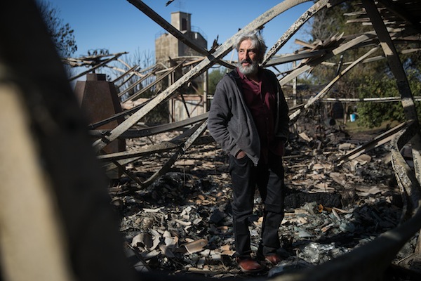 Israeli artist Yoram Ra'anan stands in what remains of his studio, which burned down completely in an overnight fire in Beit Meir, outside of Jerusalem, November 25, 2016. (Hadas Parush/Flash90)