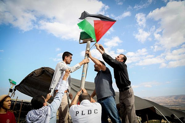 Palestinian activists raise a flag at the ‘Yasser Arafat outpost,’ a nonviolent action protesting two new Israeli settlement outposts in the area, Jordan Valley, West Bank, November 17, 2016. (Flash90)