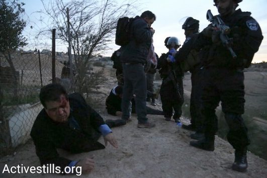 MK Ayman Odeh lies wounded from sponge-tipped bullets next to Israeli police in the Bedouin village of Umm el-Hiran, Negev, January 18, 2017. (Keren Manor/Activestills.org)