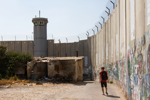 A man walks along Israel’s separation wall where it snakes through the Palestinian city of Bethlehem, August 15, 2015. (Micah Bond/Flash90)