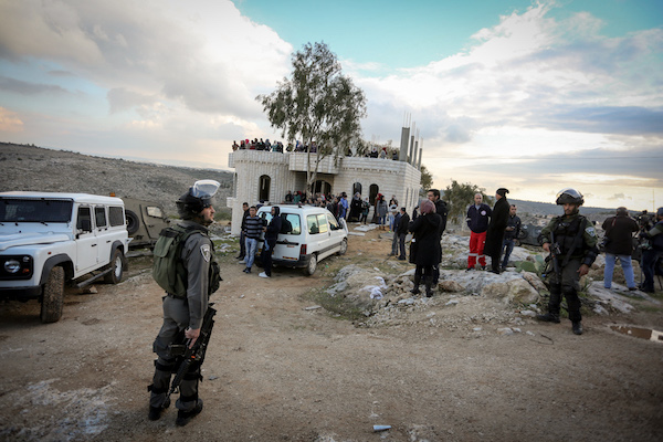 Members of Israeli security forces takes position during clashes with Palestinian protesters after attempting to demolish a house which Israeli authorities said was built without permission. Dozens of women can be seen lining the house in the background, Budrus, West Bank, January 4, 2017. (Flash90)