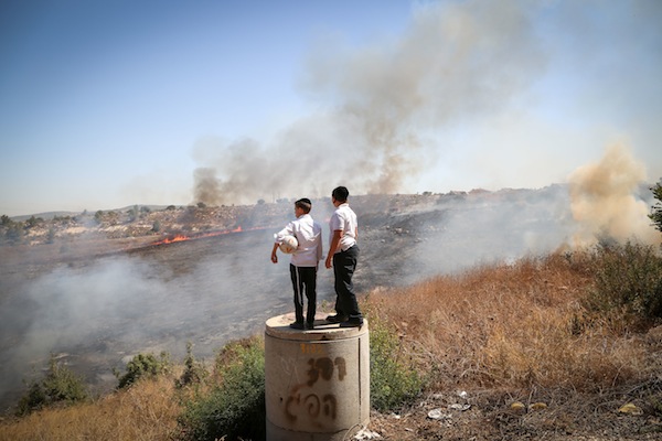 Ultra-Orthodox children look on as fire fighters try to extinguish a fire tha broke out near Ramat Beit Shemesh, outside of Jerusalem, September 20, 2016. (Yaakov Lederman/Flash90)