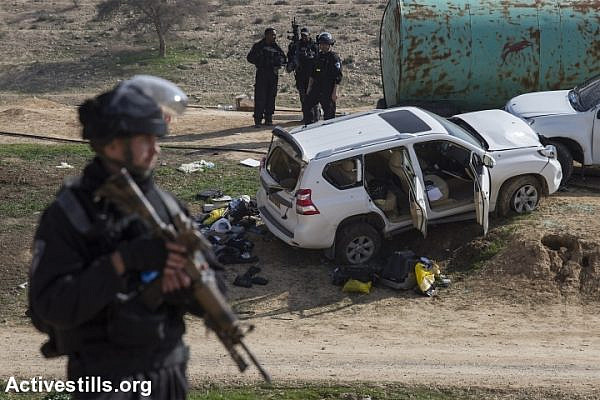 Israeli policemen stand guard in front of the car of Yaqoub Abu Al-Qi'an, who was shot dead by Israeli police in the unrecognized Bedouin village of Umm al-Hiran, in the Negev desert, January 18, 2017. (Faiz Abu Rmeleh/Activestills.org)
