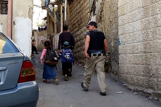 Security guards escort settler children in the neighborhood of Batan al-Hawa, East Jerusalem. December 2016. (Sarit Michaeli, B’Tselem)