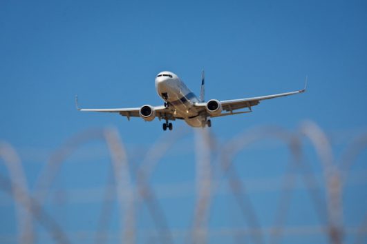An El Al plane is seen through a barbed wire fence at Tel Aviv’s Ben Gurion Airport. (Moshe Shai/Flash90)