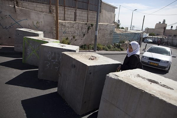 A Palestinian woman passes through concrete blocks that were installed by Israeli police in the East Jerusalem neighborhood of Jabal Mukaber, October 21, 2015. (Lior Mizrahi/Flash90)