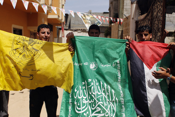 Palestinian protesters wave the flags of Palestinian political movements, Fatah (yellow) and Hamas (green) as they chant slogans in support of the national reconciliation and the announcement of the formation of a national unity government between the two factions, in Khan Yunis, in the southern Gaza Strip, on May 29, 2014. (Abed Rahim Khatib/Flash90)