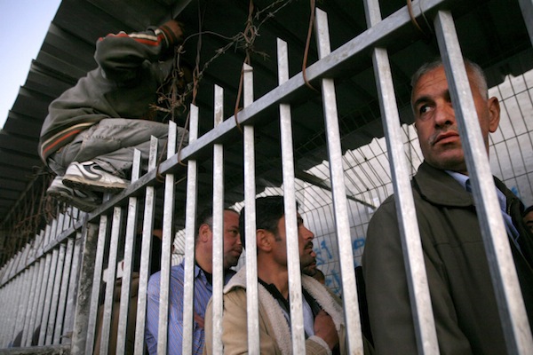 Palestinian workers stand in line next to a portion of the separation wall, waiting to cross through the checkpoint in Bethlehem into Israel, November 11, 2009. (Miriam Alster/Flash90)
