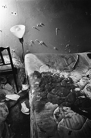 Photograph of the apartment of Fred Hampton, after the raid where he was killed by members of the Chicago Police Department. Photo shows large amount of blood on the bed that he was lying in when he was initially shot, and numerous bullet holes in the walls of the room.