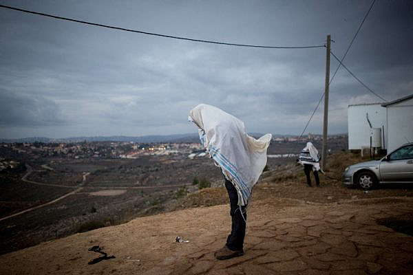 Jewish men pray early in the morning on the hill overlooking Ofra in the Jewish settlement of Amona, West Bank, December 18, 2016. (Miriam Alster/Flash90)